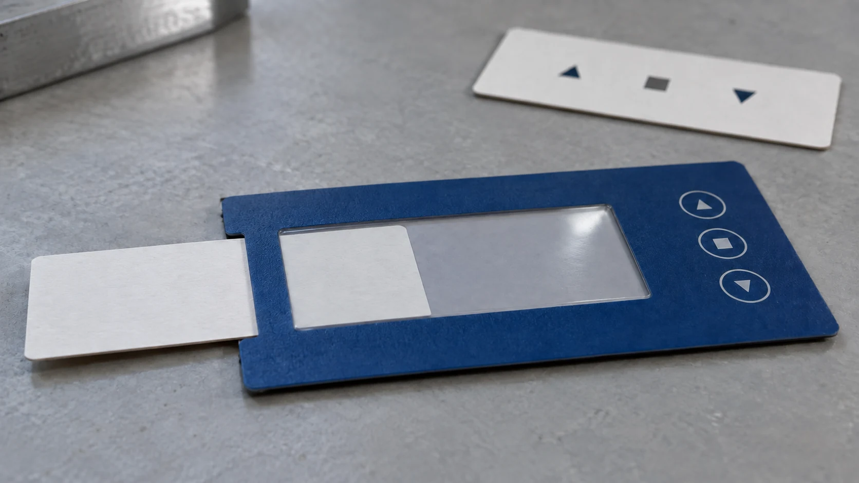 A white insert partly entering a blue overlay pocket from the left, with a spare symbol strip behind it.