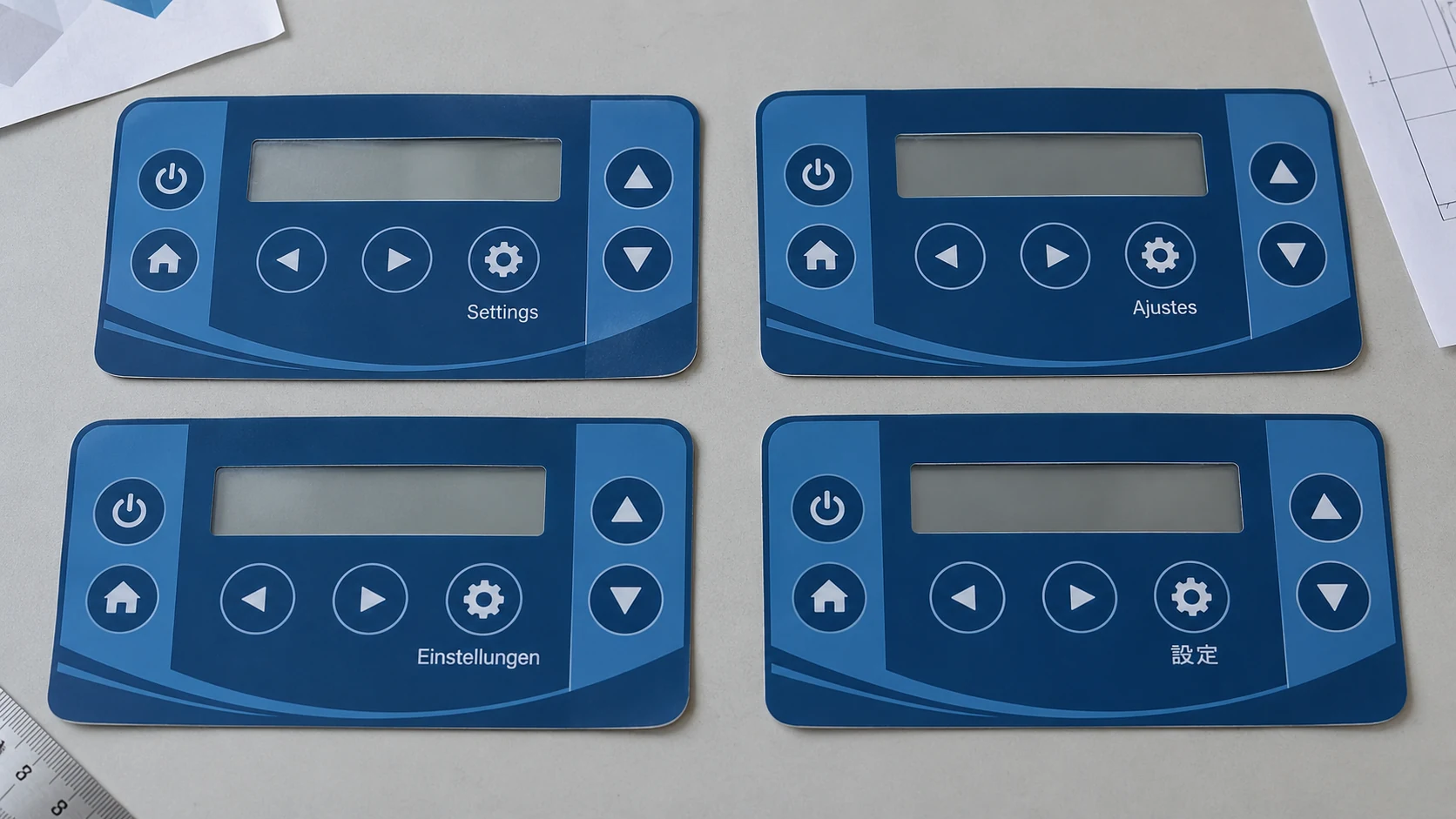 Four blue graphic overlays with matching control layouts and settings labels in English, Spanish, German and Japanese.